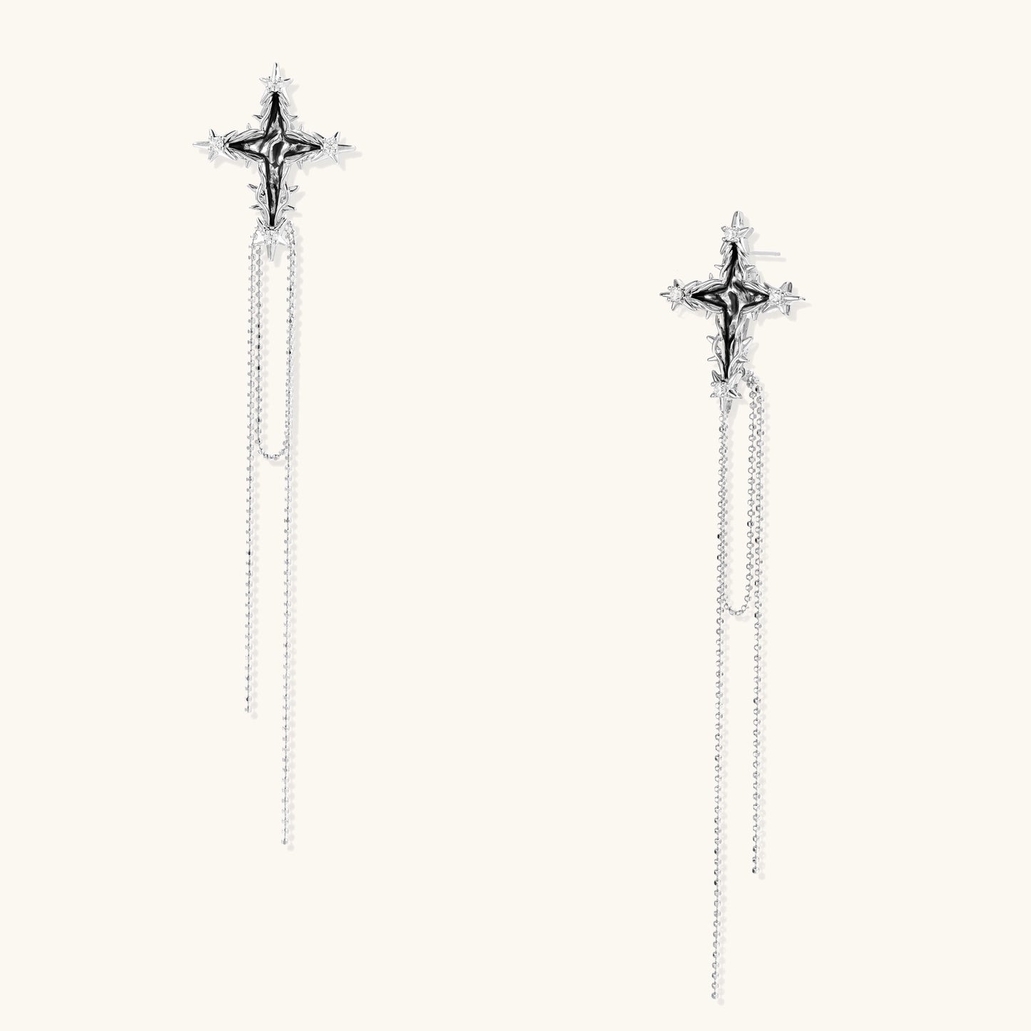 Long silver-toned cross earrings with star accents and delicate chain dangles on white background.