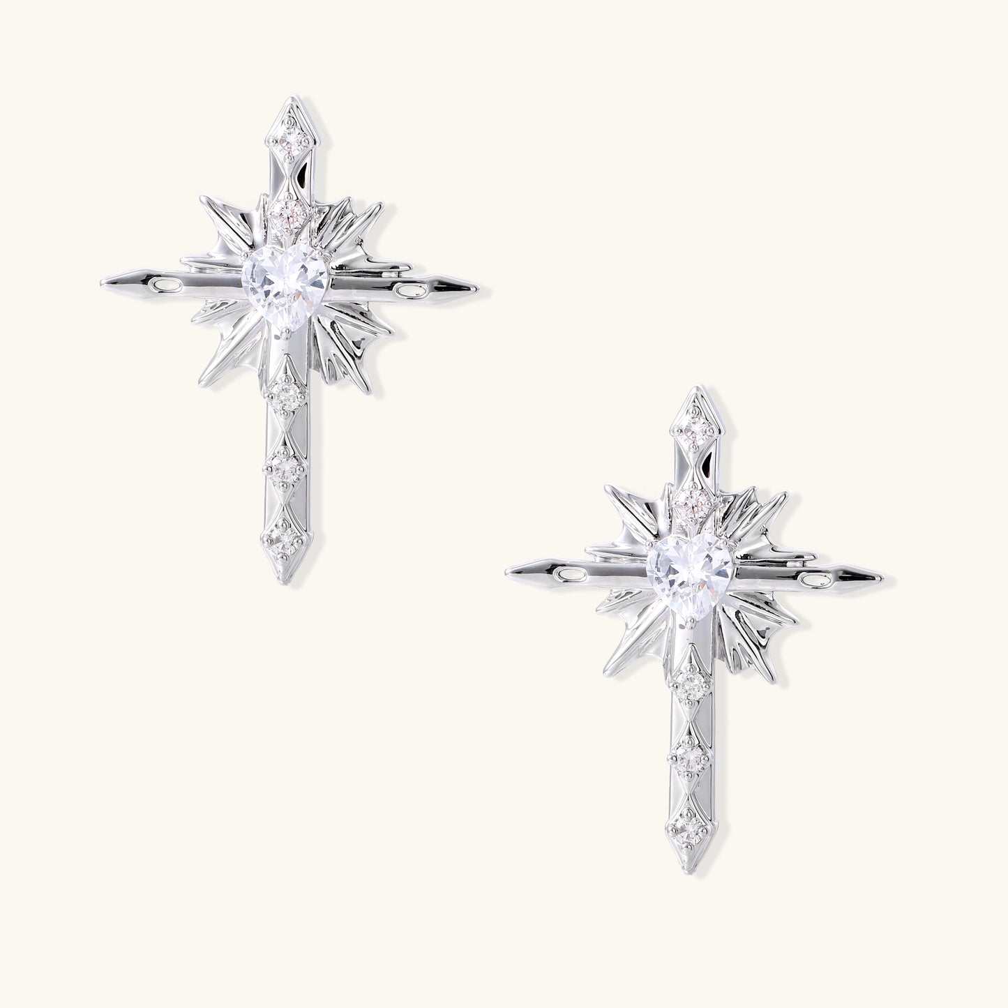 Gold-plated brass starburst cross earrings with central zirconia stones on white background.