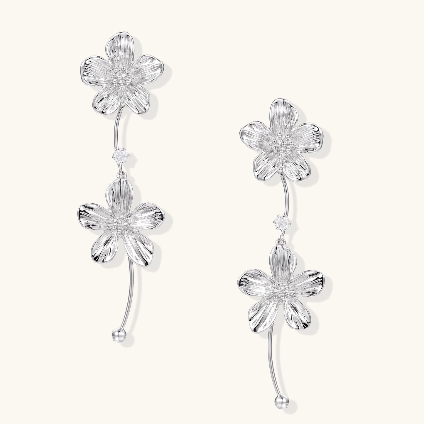 Gold-plated floral dangle earrings with zirconia crystal centers and curved stems on white background.