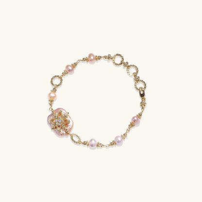 Gold-plated chain bracelet with baroque pearl centerpiece and floral charm, featuring mixed freshwater pearls.