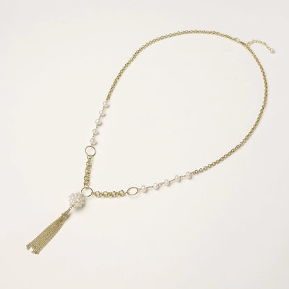 Layered gold-plated necklace with freshwater pearls, central pearl cluster, and chain tassel on cream background.