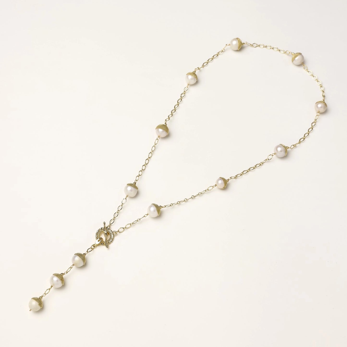 Long gold-plated lariat necklace featuring baroque pearls with metal caps arranged in elegant Y-shape design