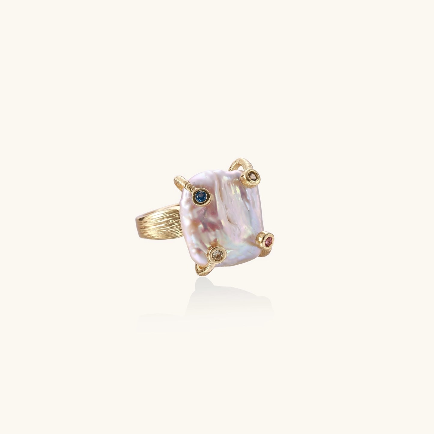 Gold-plated ring featuring large baroque freshwater pearl with small colorful gemstone accents on textured band