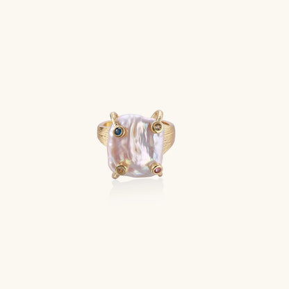 Gold-plated ring featuring large baroque freshwater pearl with small colorful gemstone accents on textured band