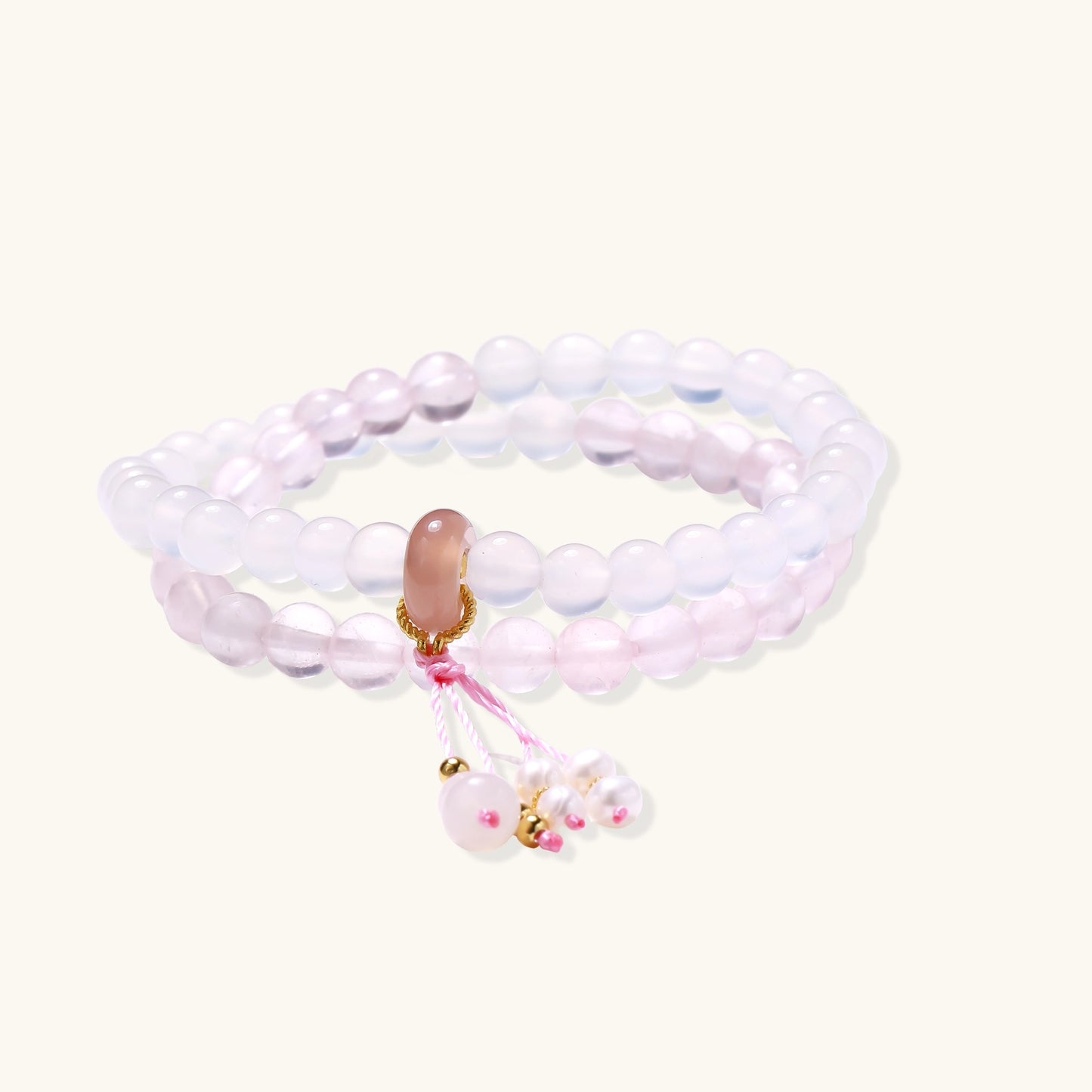 Stretchable bracelet with pink rose quartz and white agate beads, featuring a decorative tassel pendant on white background.