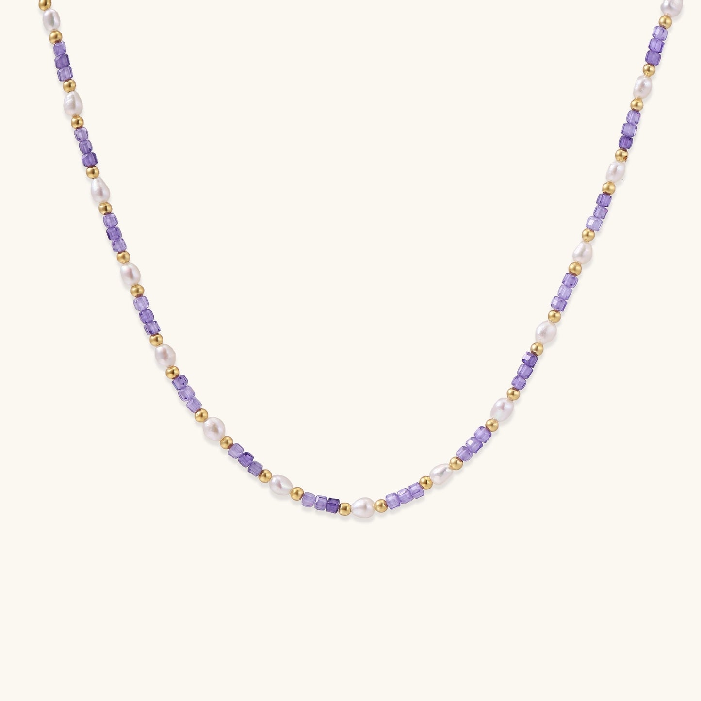 Delicate beaded necklace with alternating purple zirconia stones, white freshwater pearls, and gold-plated spacers on cream background.