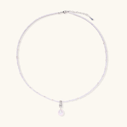 Delicate beaded necklace with lavender crystals, white pearls, and crystal pendant with pearl drop on white background.
