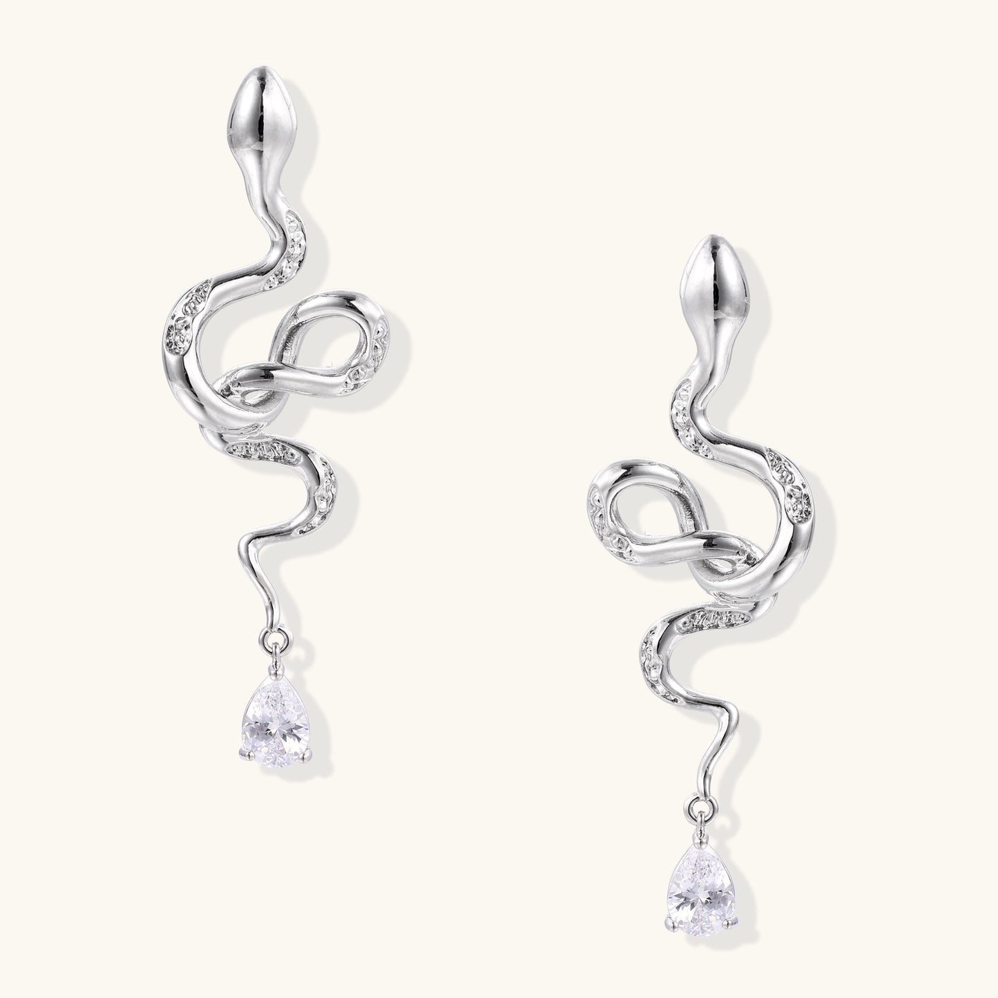 Coiled gold-plated snake earrings with zirconia stones and teardrop crystal dangles against white background.