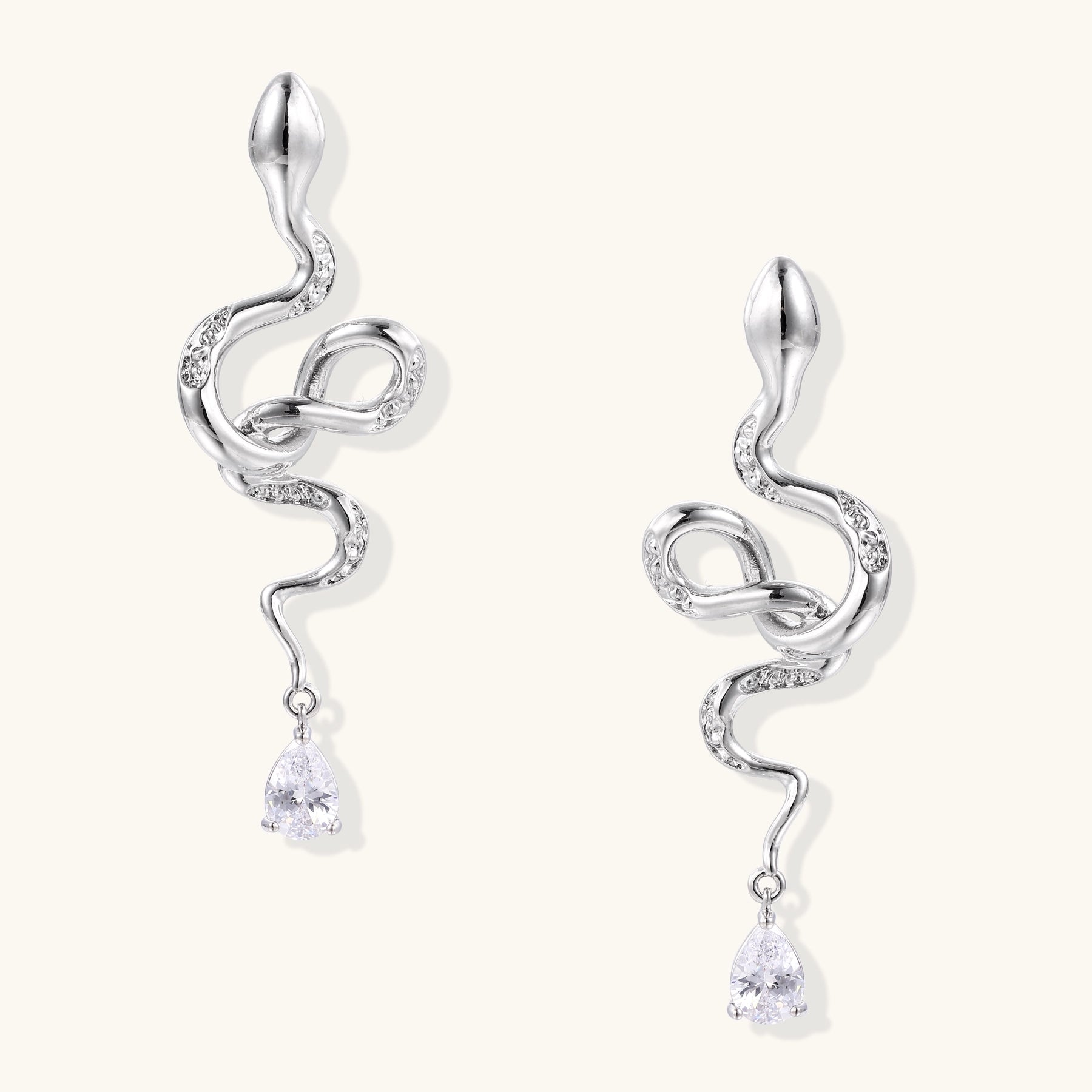 Coiled gold-plated snake earrings with zirconia stones and teardrop crystal dangles against white background.