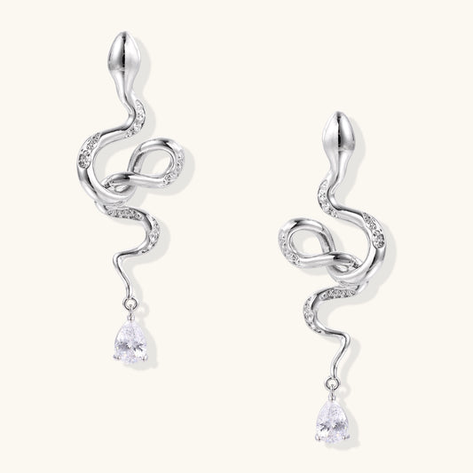 Coiled gold-plated snake earrings with zirconia stones and teardrop crystal dangles against white background.