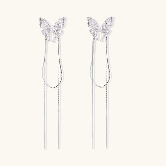 Delicate drop earrings with clear crystal butterfly tops and long metallic chain dangles on white background.