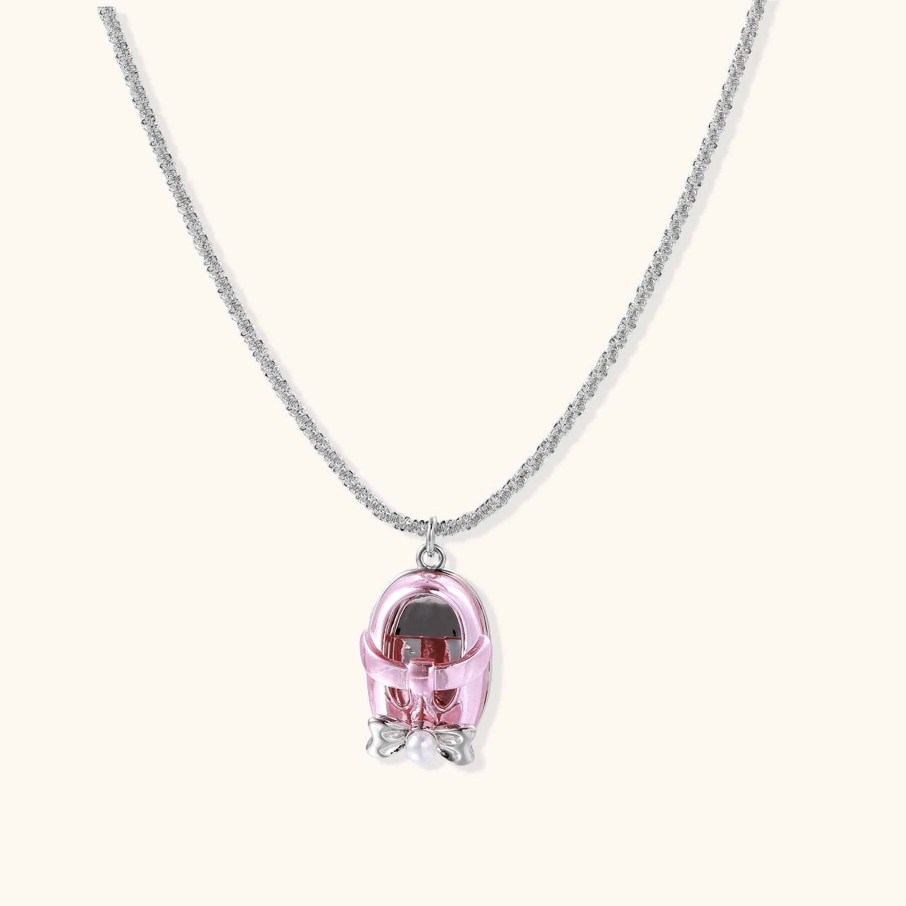 Delicate gold-plated chain necklace with transparent pink-tinted capsule pendant containing decorative bow element