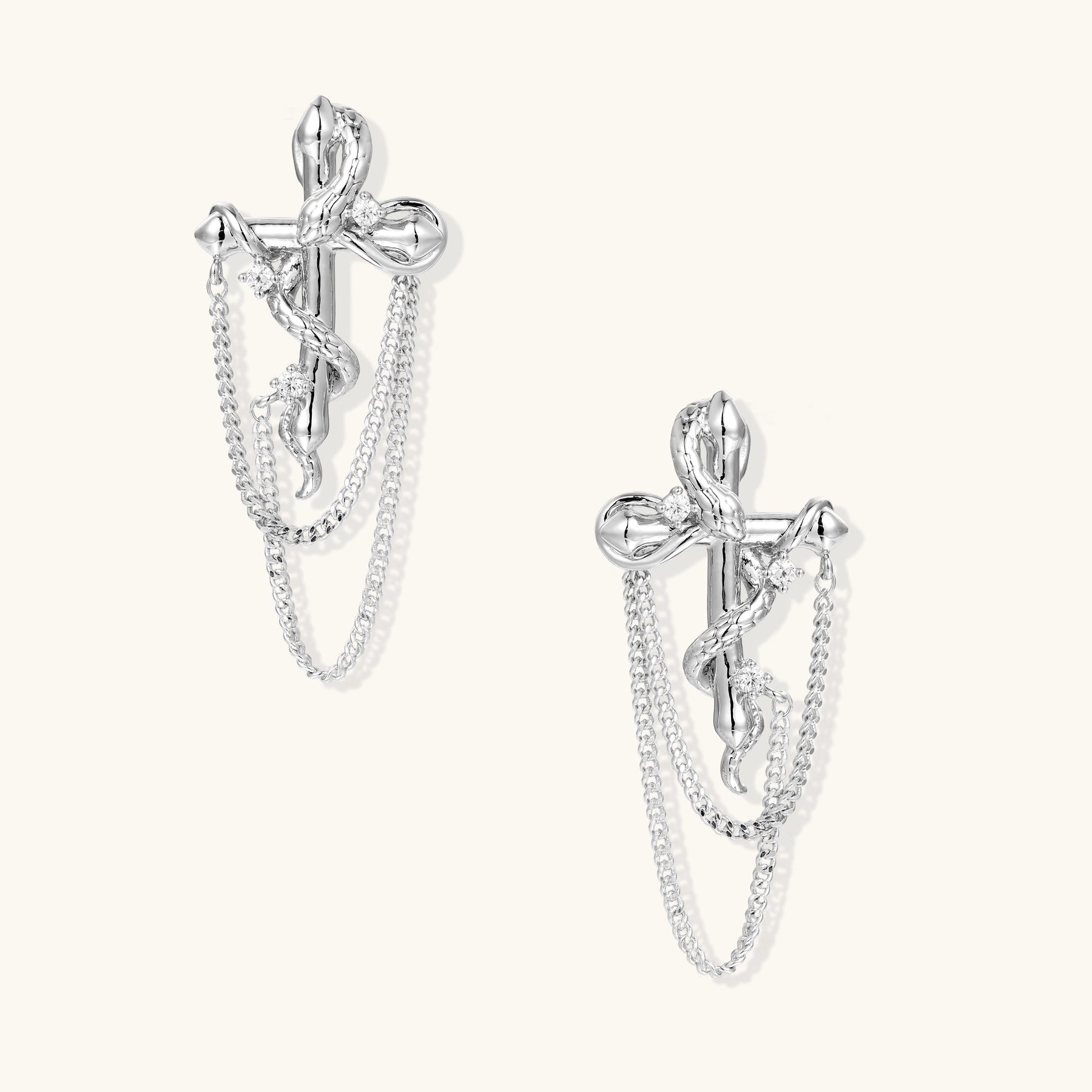 Silver-toned bow-shaped earrings with dangling chain details and zirconia accents on neutral background.