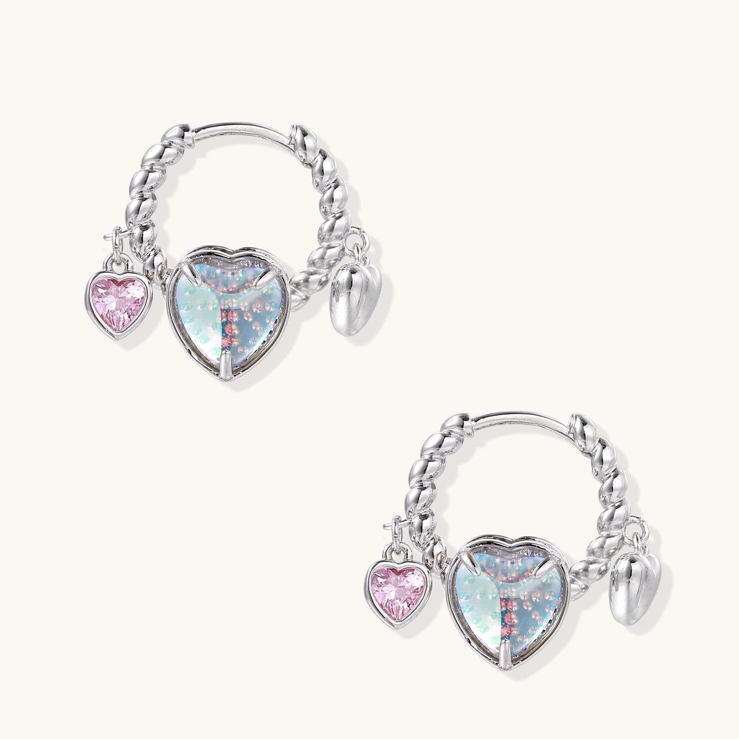 Gold-plated brass hoop earrings with three heart charms including iridescent turquoise and pink hearts on white background.