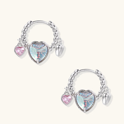 Gold-plated brass hoop earrings with three heart charms including iridescent turquoise and pink hearts on white background.