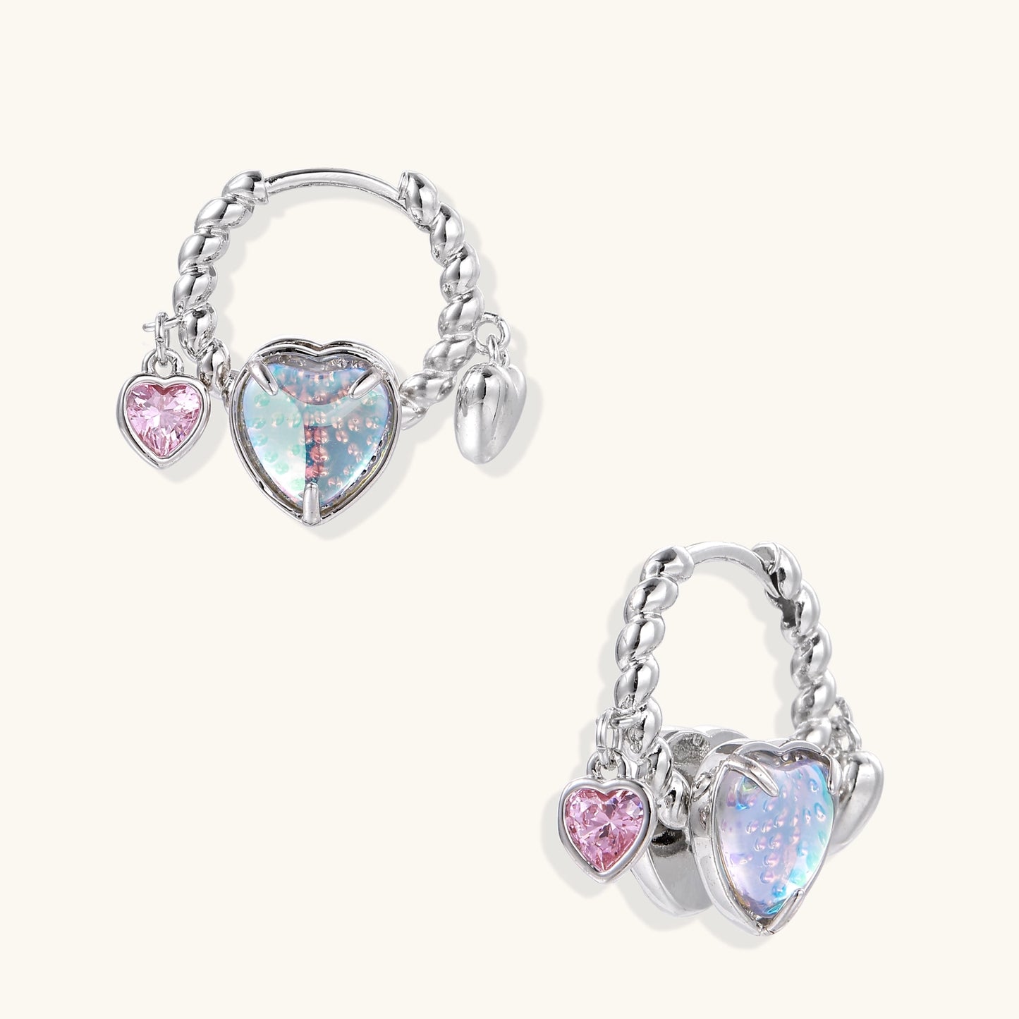 Gold-plated brass hoop earrings with three heart charms including iridescent turquoise and pink hearts on white background.