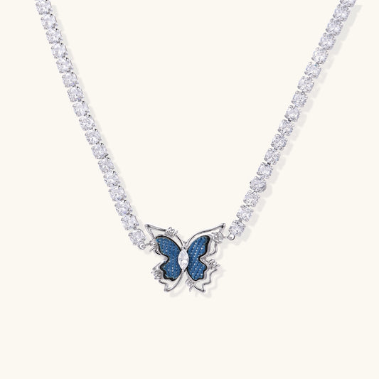 Gold-plated tennis chain necklace with blue denim butterfly pendant and zirconia stones on light background.