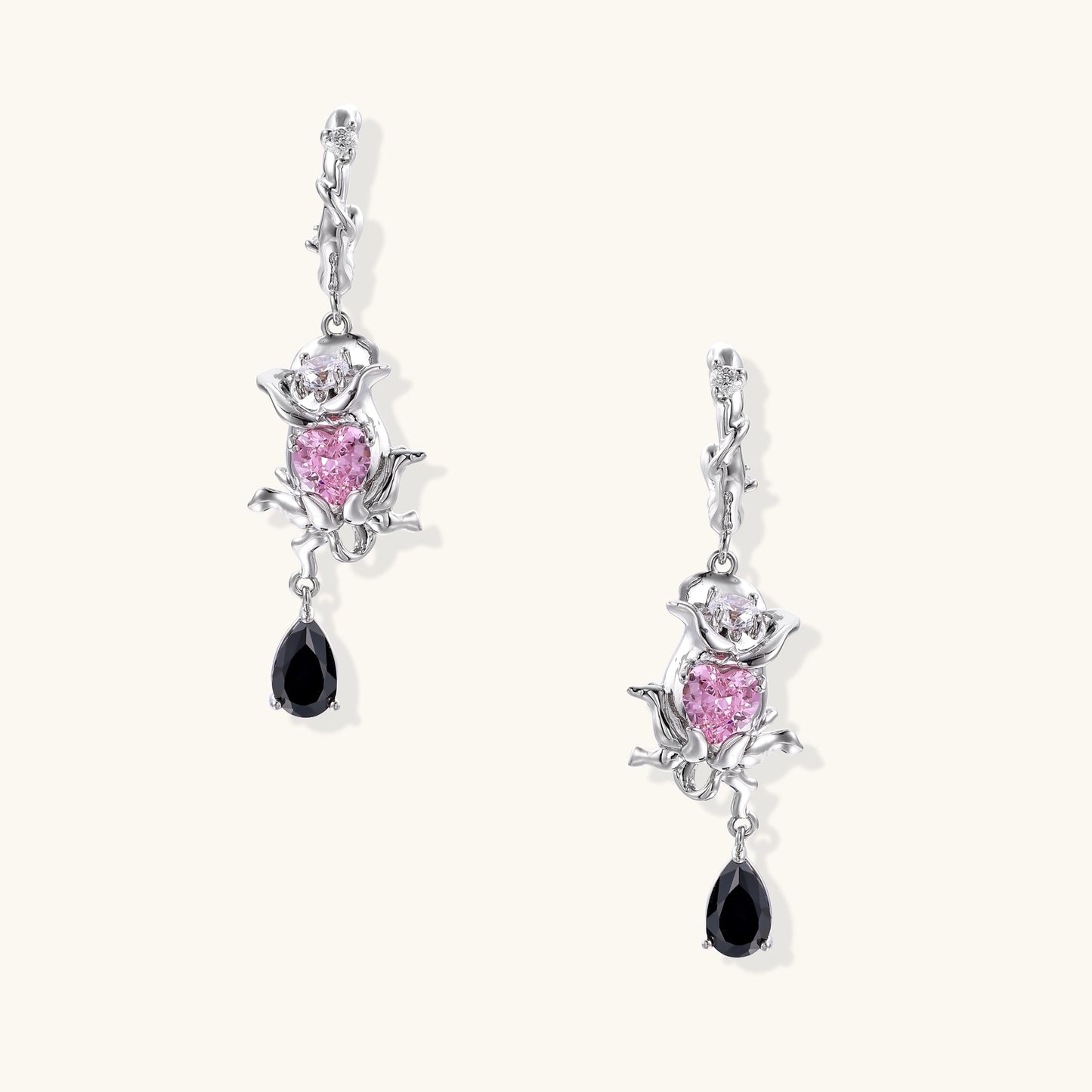 Gothic romantic dangle earrings featuring thorny rose design with pink zirconia and black teardrop elements on white background
