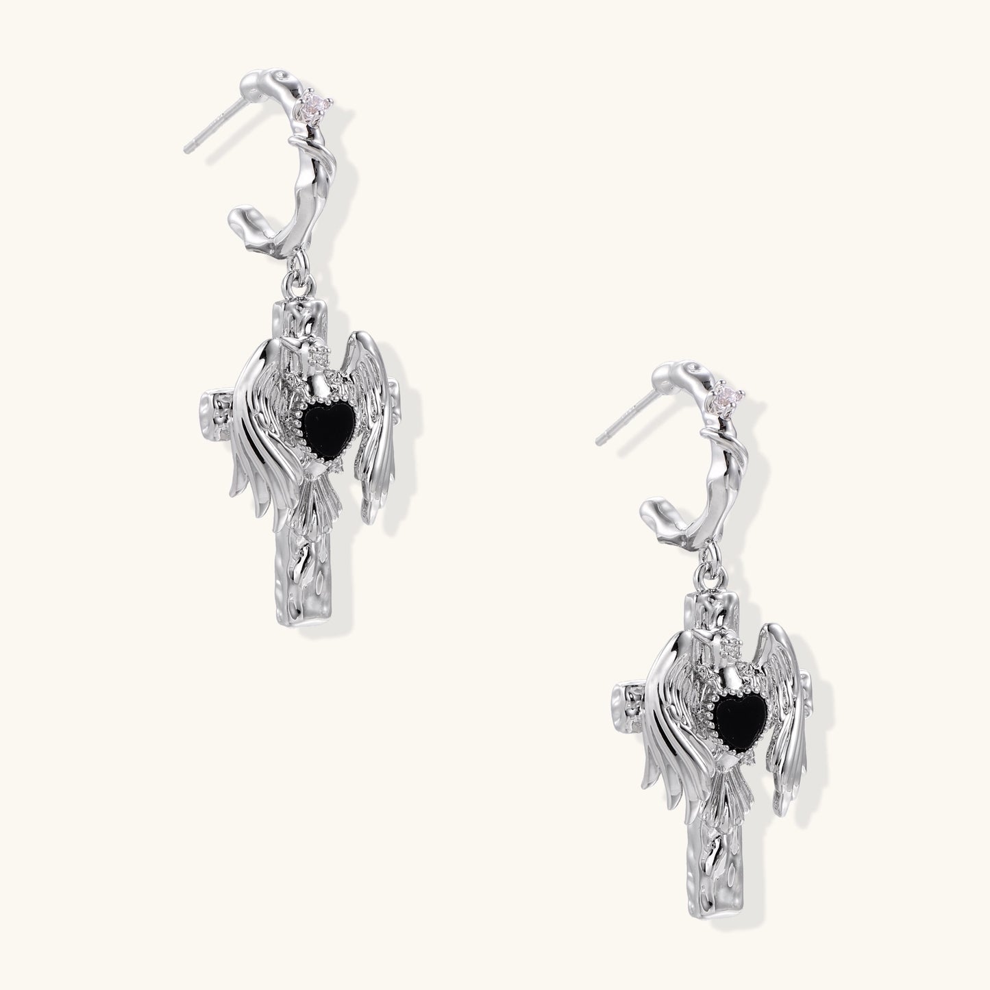 Gold-plated brass earrings with winged design, black heart-shaped zirconia center, and crystal accents on white background.