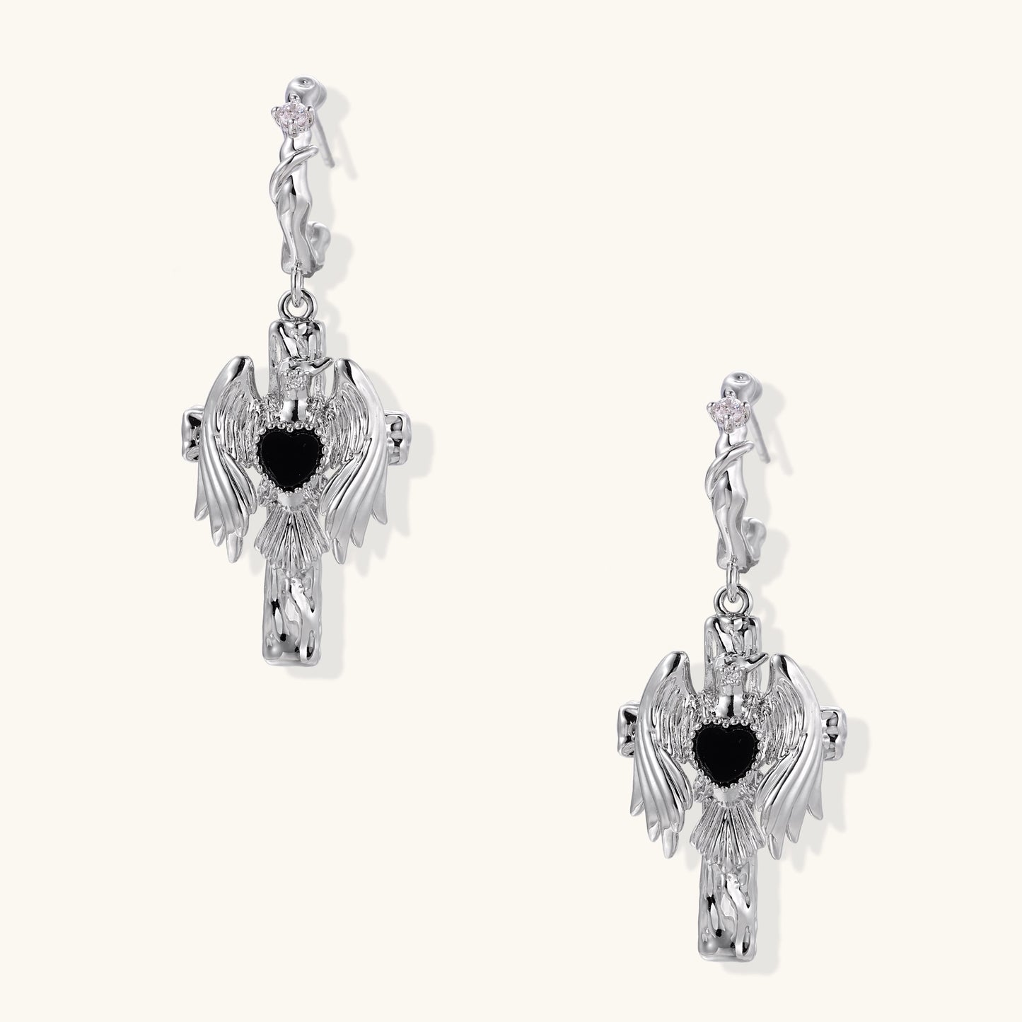 Gold-plated brass earrings with winged design, black heart-shaped zirconia center, and crystal accents on white background.