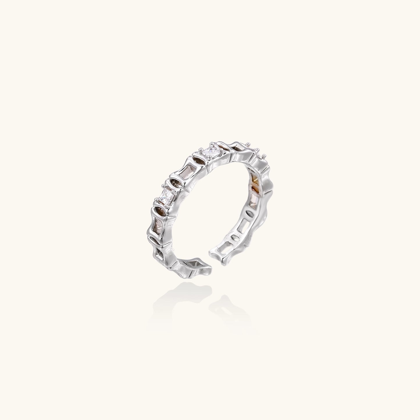 Close-up of geometric gold-plated ring with alternating rectangular blocks and zirconia crystals on white background.