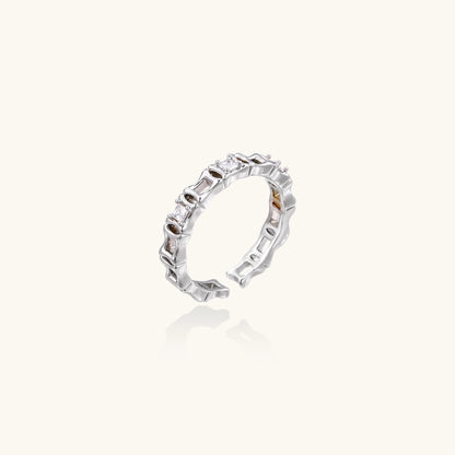 Close-up of geometric gold-plated ring with alternating rectangular blocks and zirconia crystals on white background.