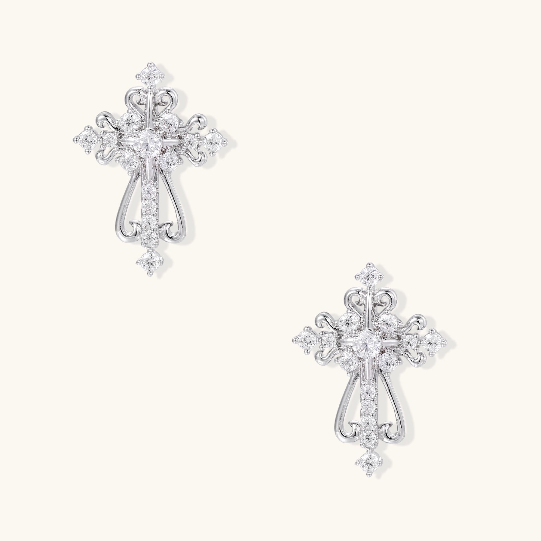 Ornate gold-plated cross dangle earrings with baroque scrollwork details and sparkling zirconia stones on neutral background