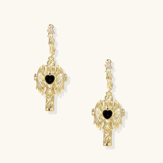 Ornate gold-plated drop earrings featuring wing designs with black zirconia heart centers on light background.