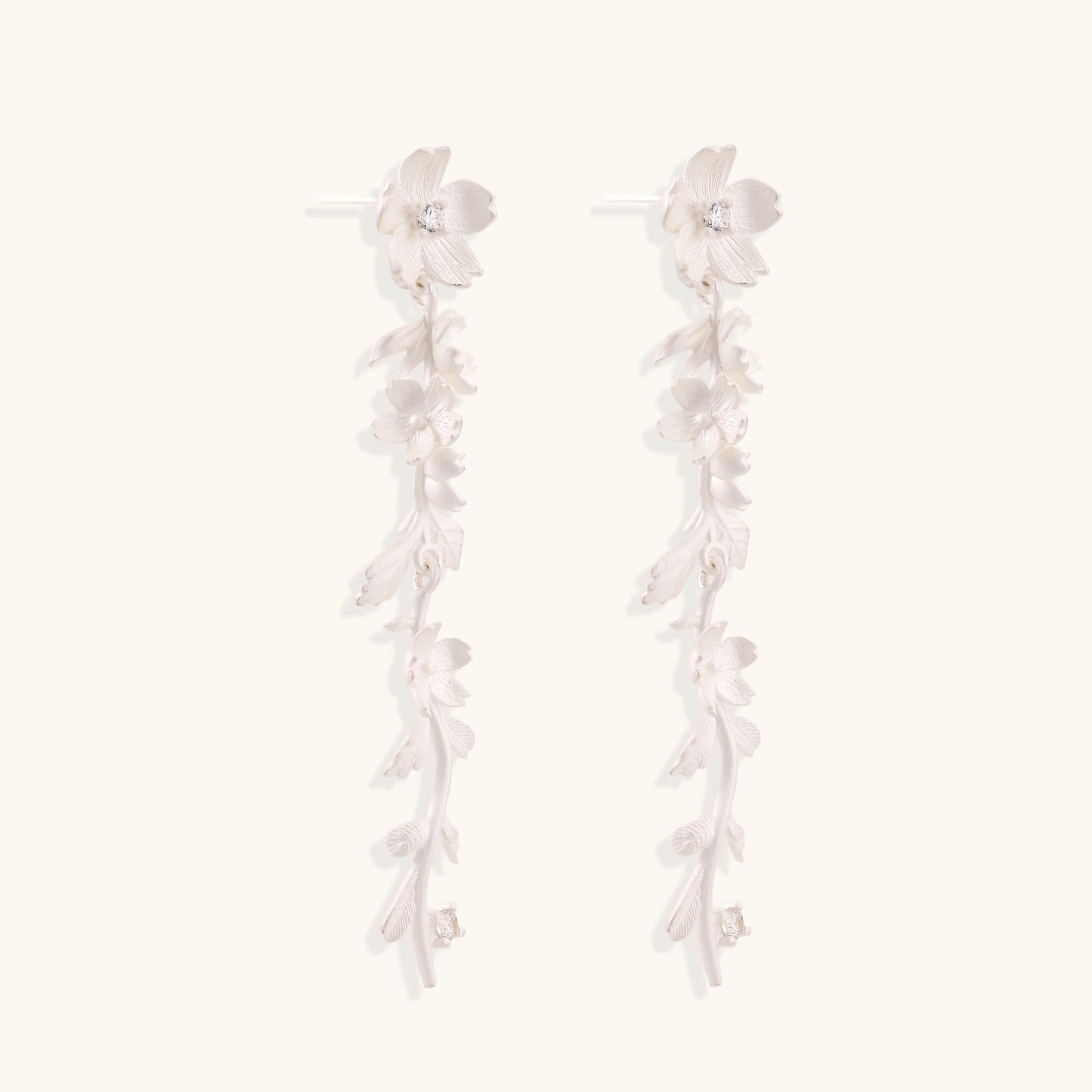 Pair of sterling silver dangle earrings with intricate leaf vine patterns and crystal accents on white background.