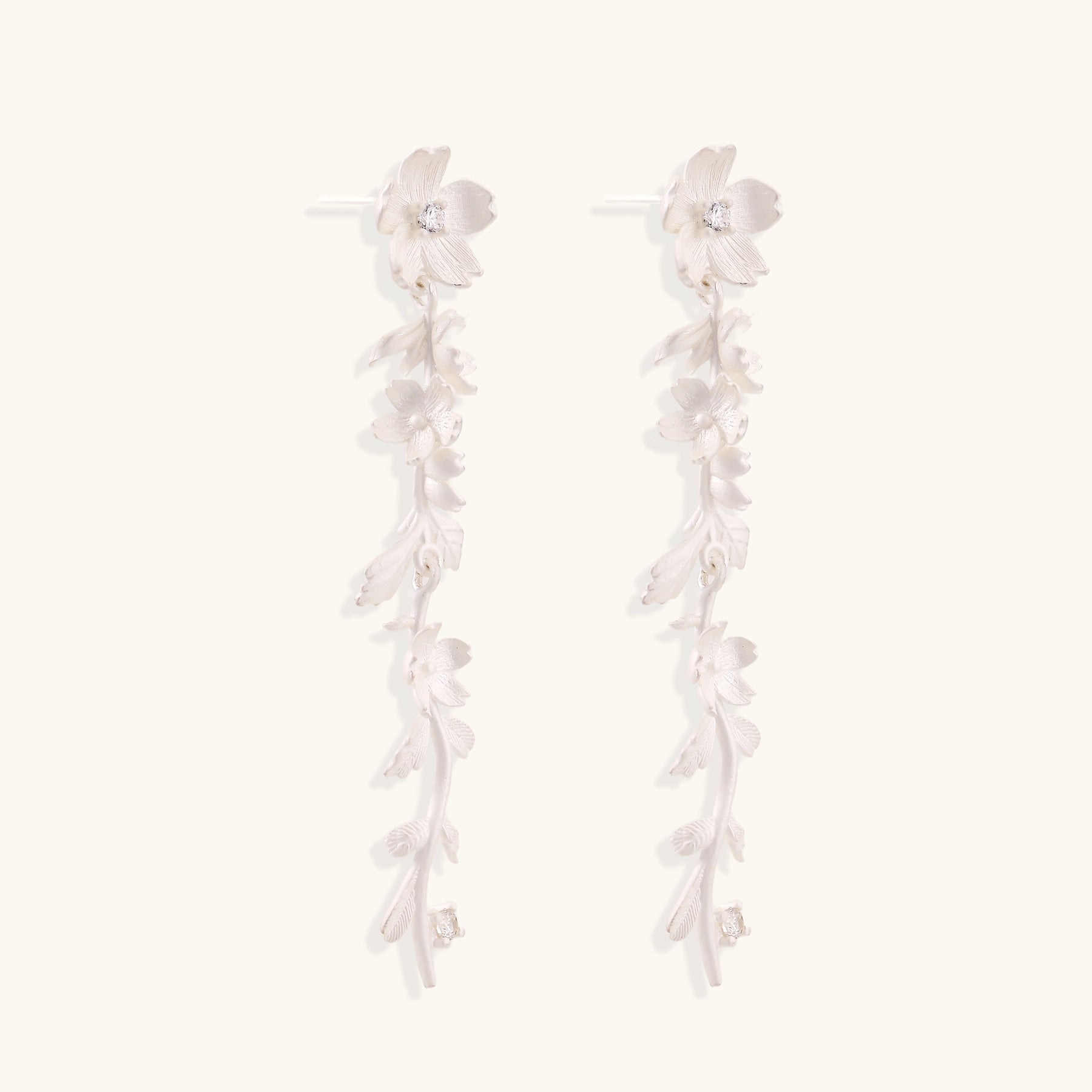 Pair of sterling silver dangle earrings with intricate leaf vine patterns and crystal accents on white background.