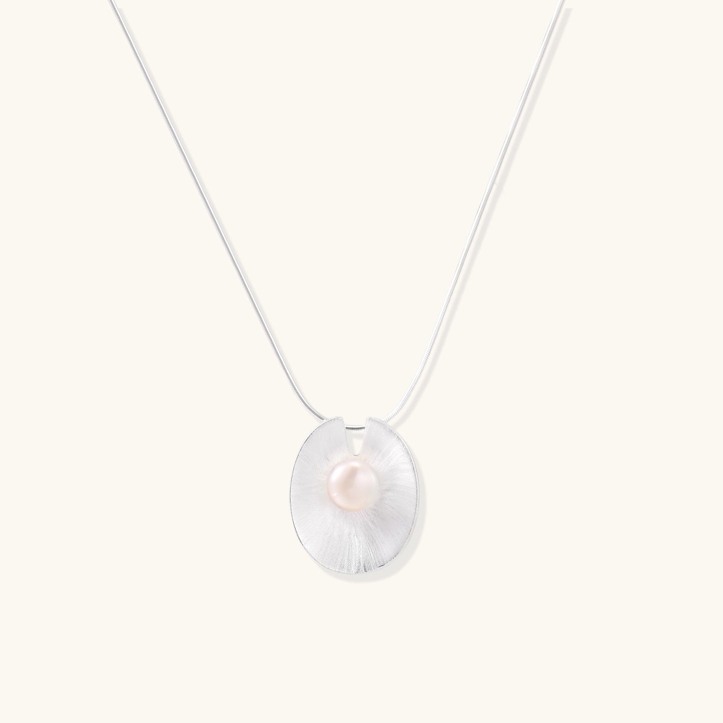 Delicate sterling silver necklace with oval iridescent pendant and central freshwater pearl on white background
