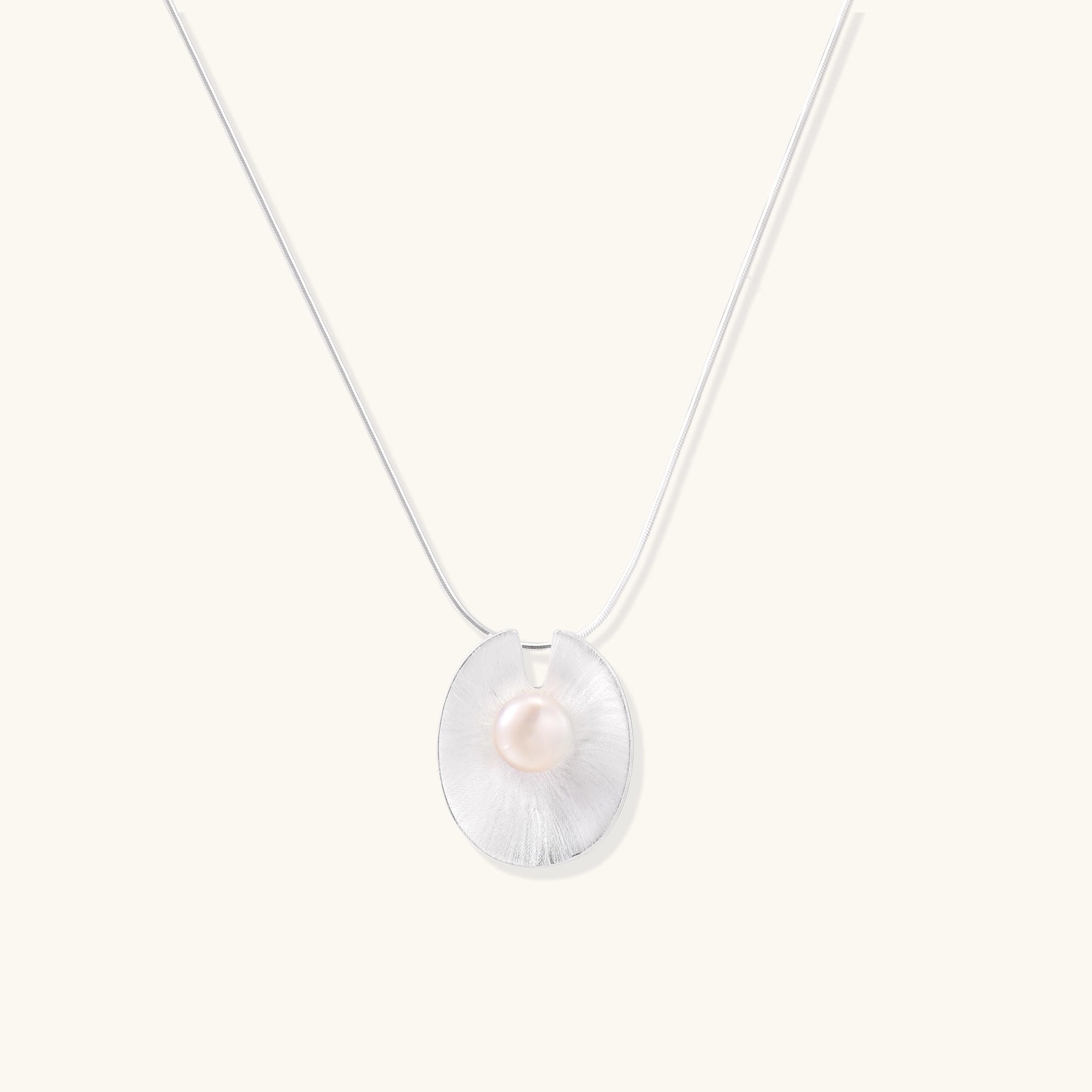 Delicate sterling silver necklace with oval iridescent pendant and central freshwater pearl on white background