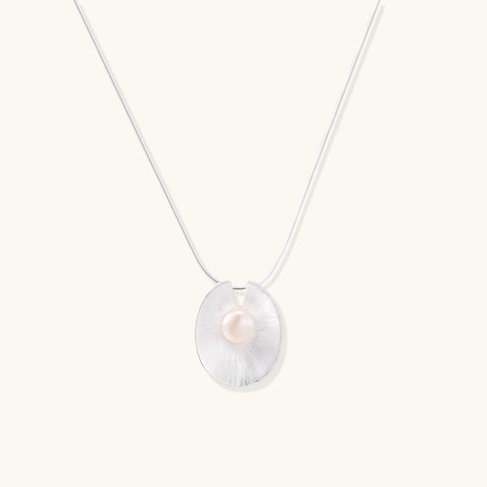 Delicate sterling silver necklace with oval iridescent pendant and central freshwater pearl on white background