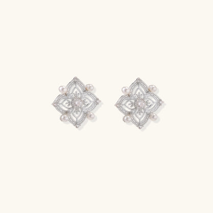 Detailed view of sterling silver stud earrings with geometric filigree design and small freshwater pearls on white background.