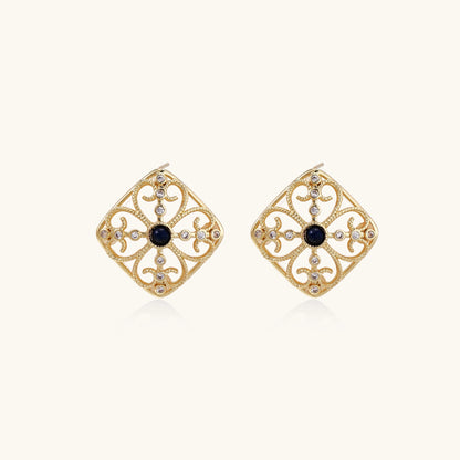 Ornate 18K gold plated stud earrings with intricate filigree design and central lapis lazuli stones on cream background.