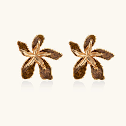 Large gold-plated flower earrings with brown enamel marbled petals on beige background, showing intricate floral design.