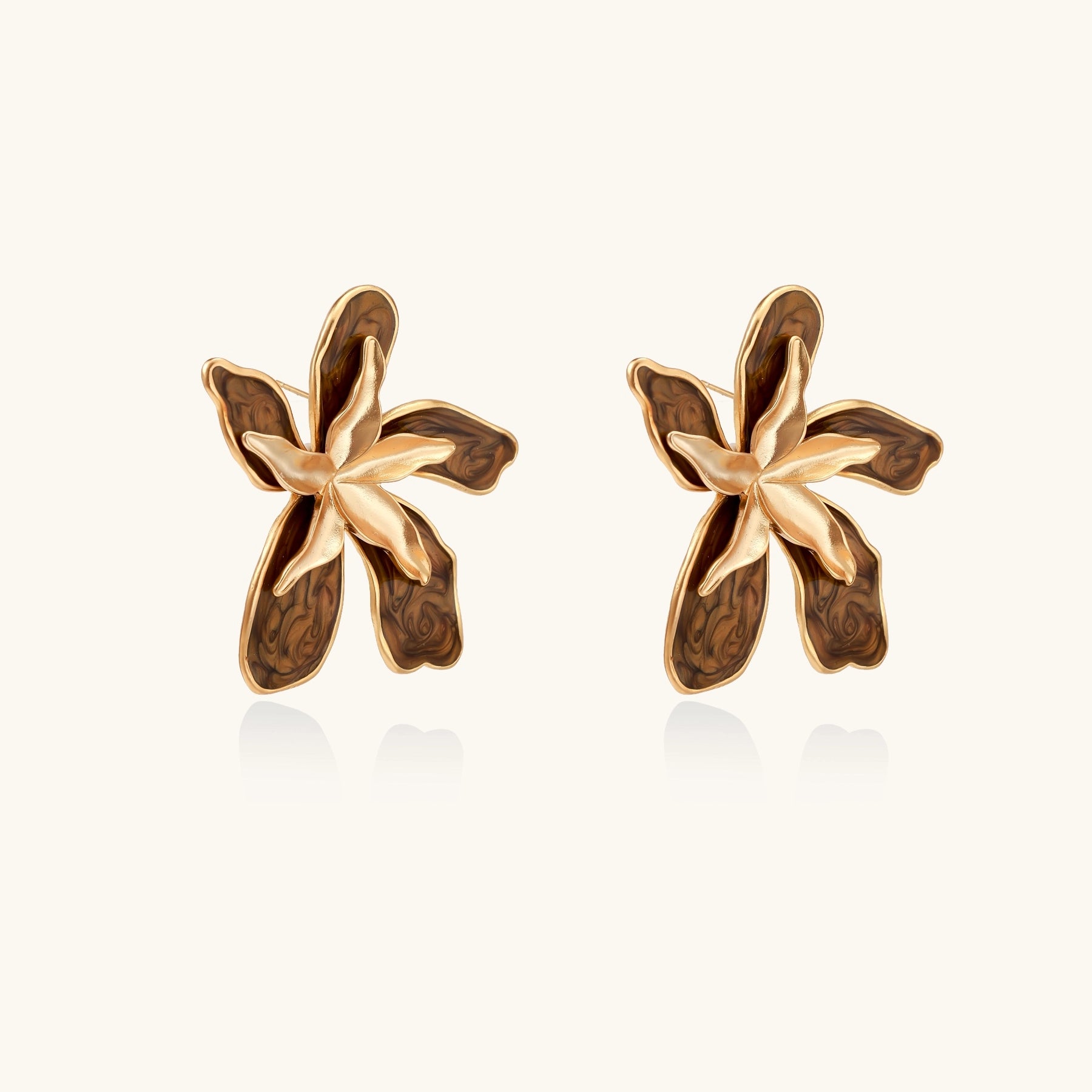 Large gold-plated flower earrings with brown enamel marbled petals on beige background, showing intricate floral design.