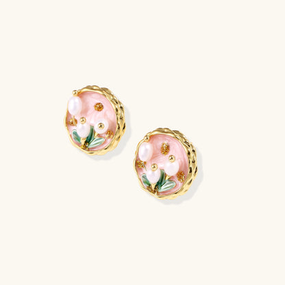 Round stud earrings with pink enamel background, white pearl tulips, green leaves, and twisted gold border on white background.