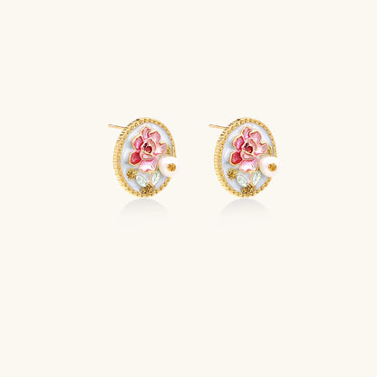 Round gold-plated stud earrings featuring pink enamel roses with freshwater pearl accents on white background.