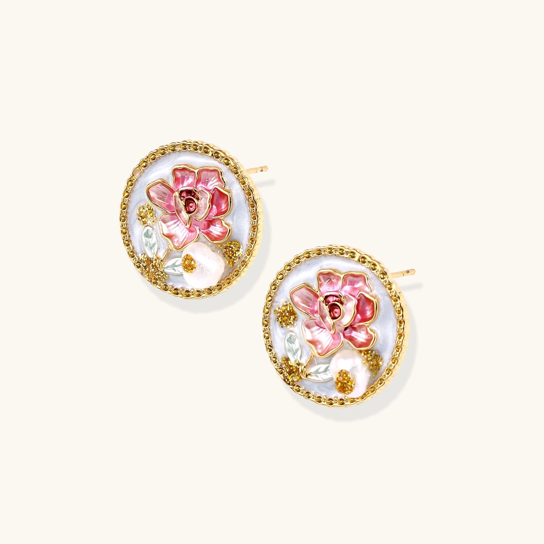 Round gold-plated stud earrings featuring pink enamel roses with freshwater pearl accents on white background.