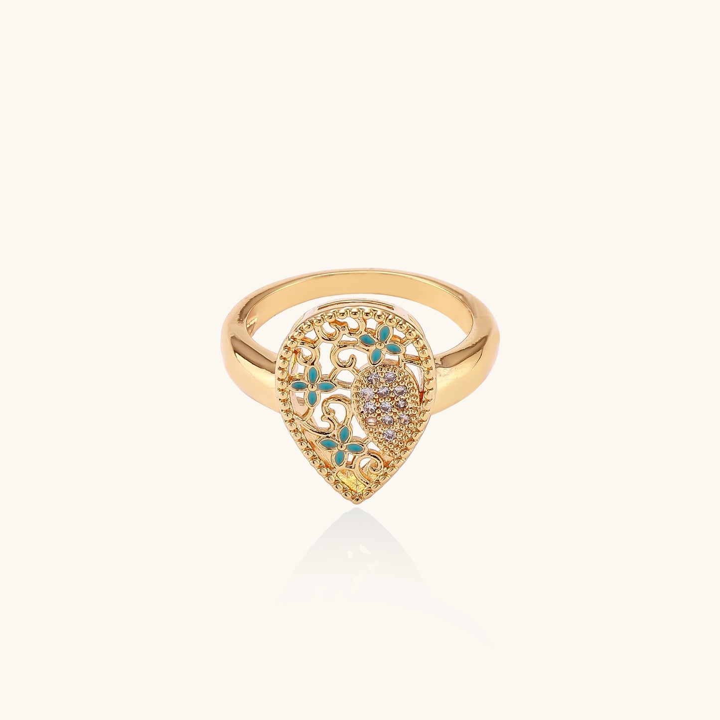 Gold-plated heart ring with turquoise enamel scrollwork and cubic zirconia stones on white background