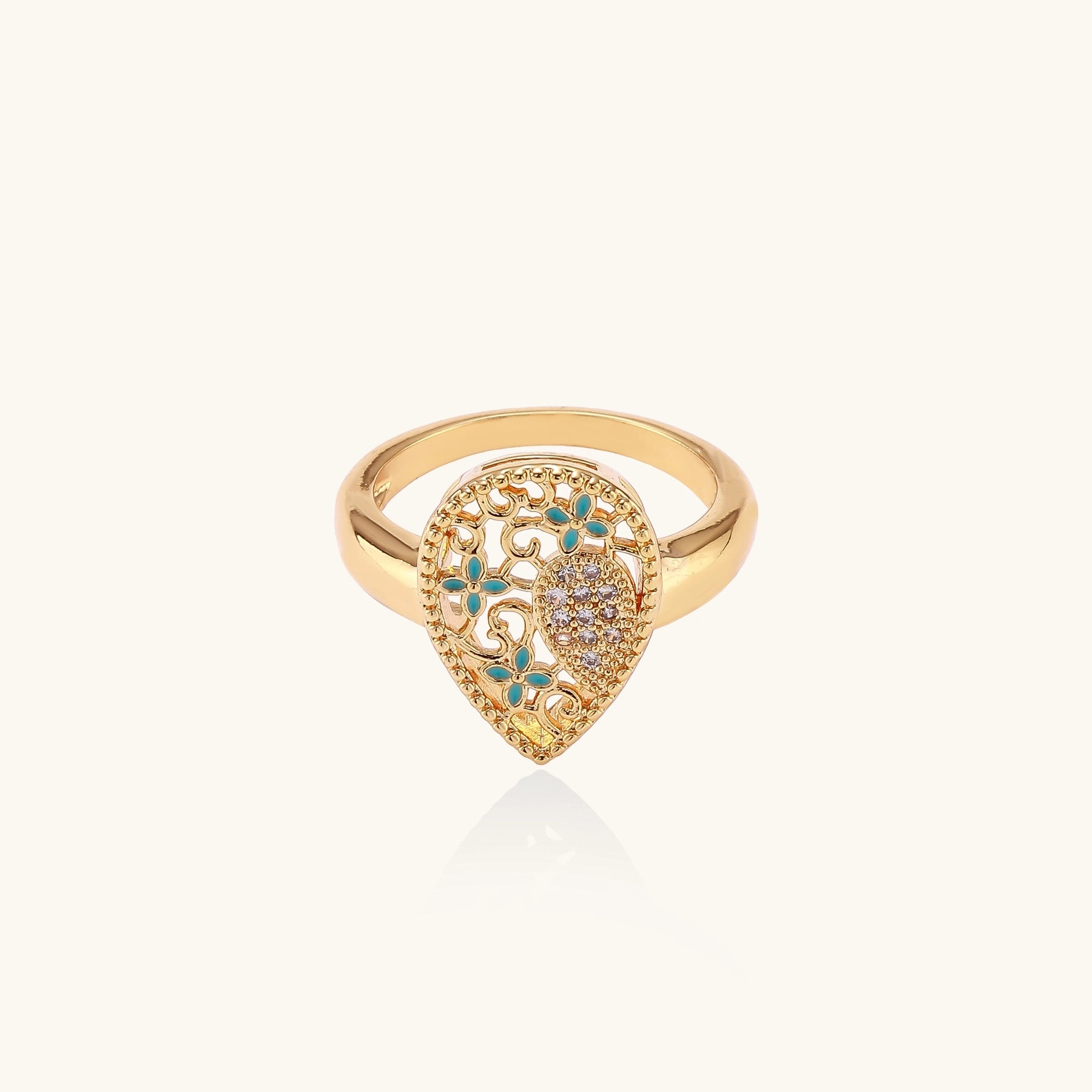 Gold-plated heart ring with turquoise enamel scrollwork and cubic zirconia stones on white background