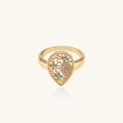 Gold-plated heart ring with turquoise enamel scrollwork and cubic zirconia stones on white background