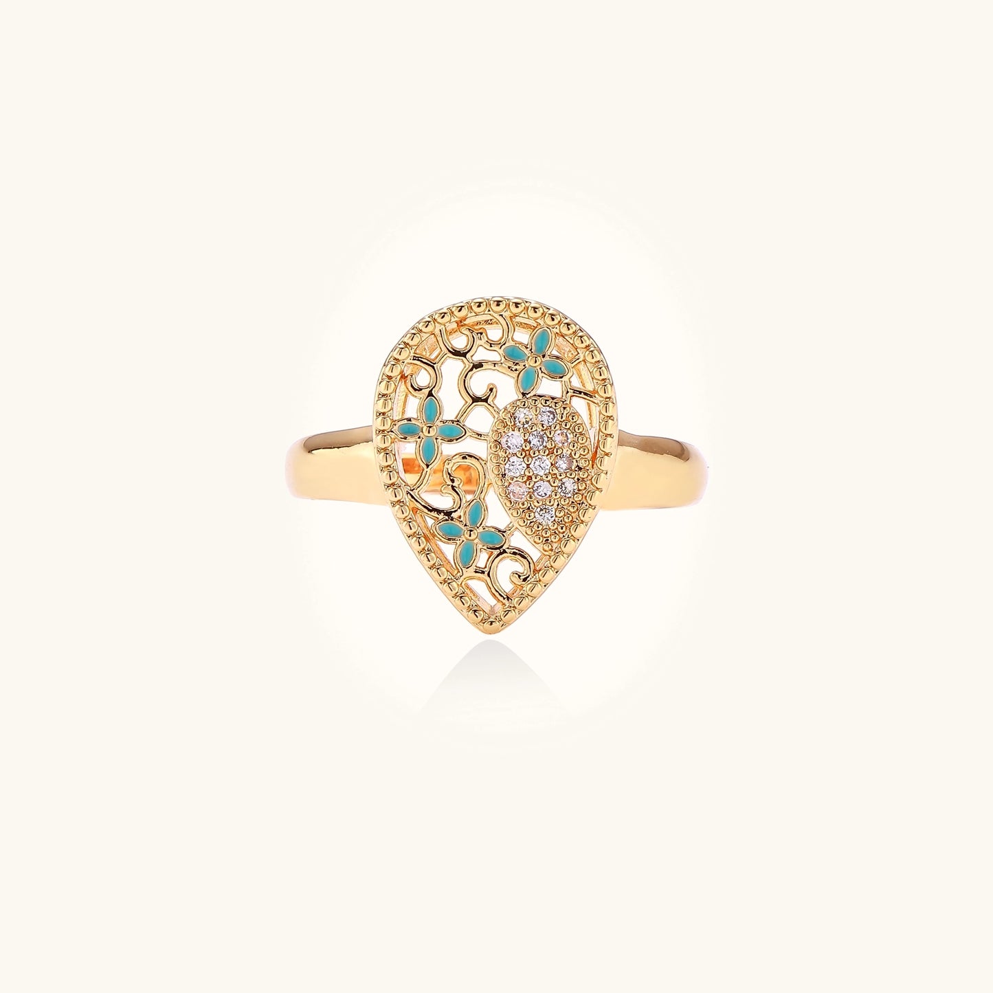 Gold-plated heart ring with turquoise enamel scrollwork and cubic zirconia stones on white background