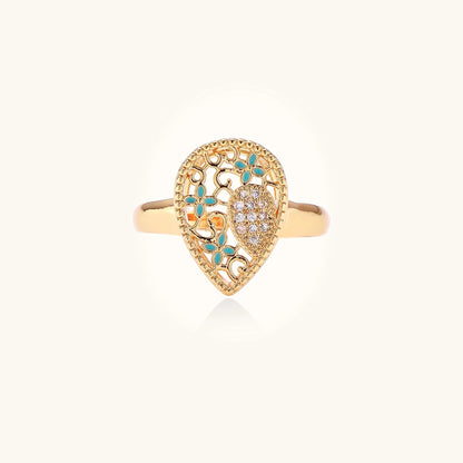 Gold-plated heart ring with turquoise enamel scrollwork and cubic zirconia stones on white background
