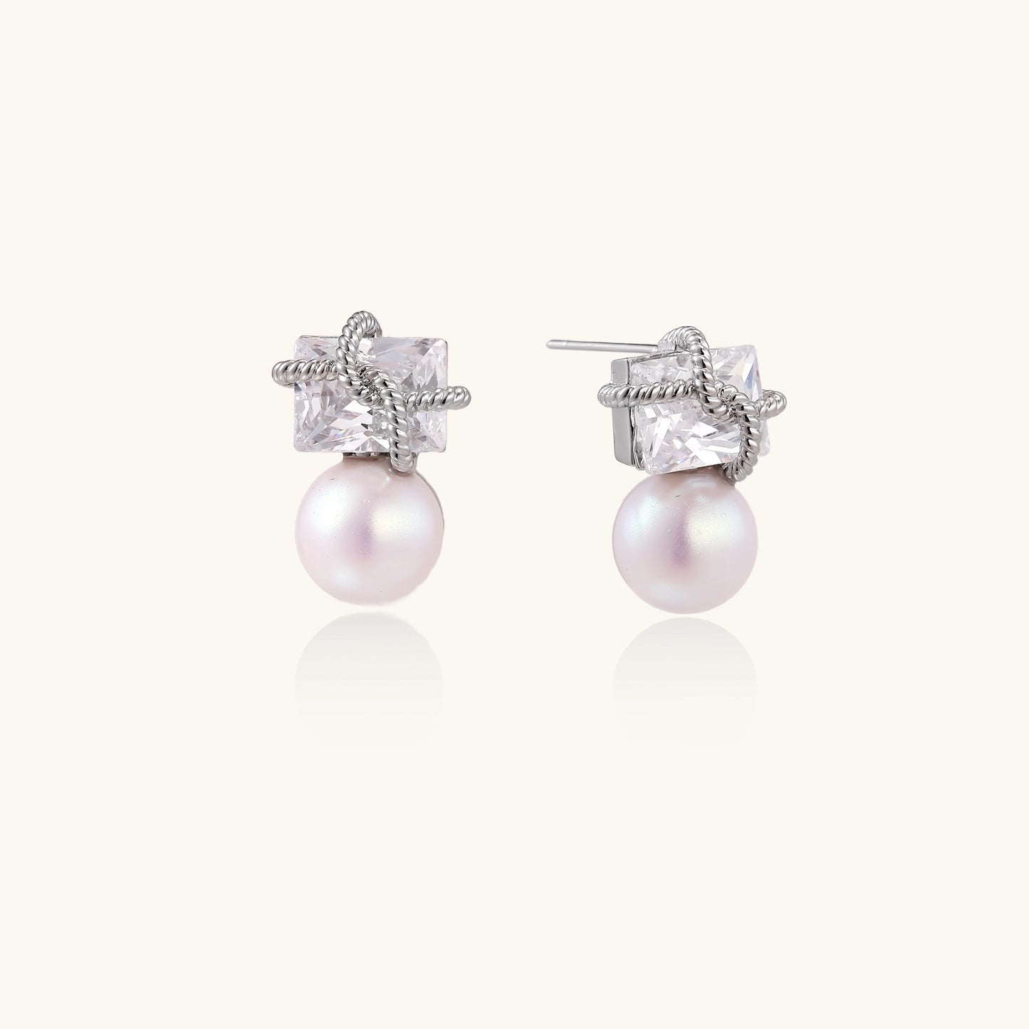 Gold-plated stud earrings with square crystal tops wrapped in twisted wire and freshwater pearl drops on white background