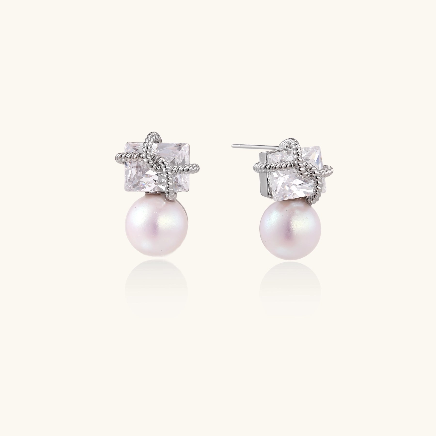 Gold-plated stud earrings with square crystal tops wrapped in twisted wire and freshwater pearl drops on white background