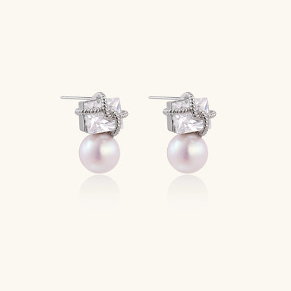 Gold-plated stud earrings with square crystal tops wrapped in twisted wire and freshwater pearl drops on white background