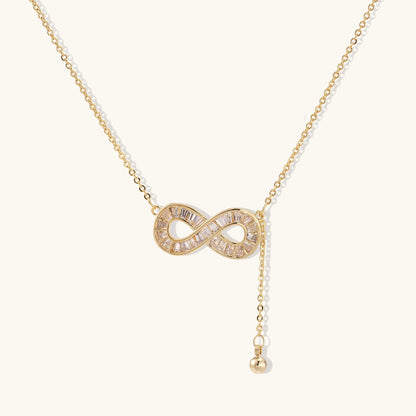 Delicate 14K gold plated infinity pendant with crystal accents on adjustable chain with small ball charm detail.