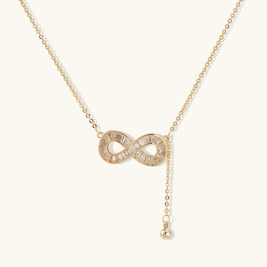 Delicate 14K gold plated infinity pendant with crystal accents on adjustable chain with small ball charm detail.